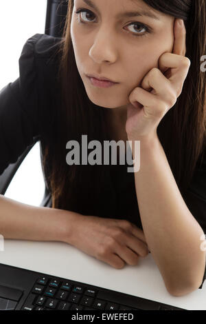 office worker sitting at her desk deep in thought but looking unhappy about something Stock Photo