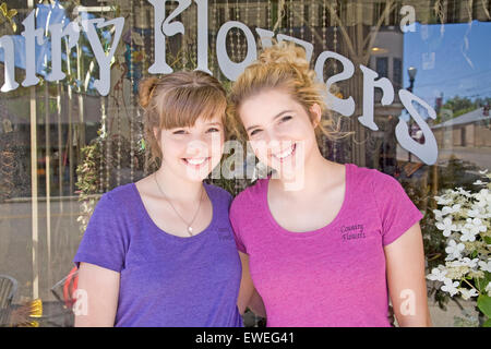 Two pretty teen-aged girls, who are sisters, stand in front of their grandmother's store in a small town in northern Oregon. Stock Photo