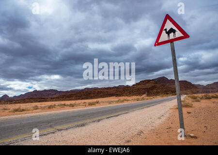 Country Road in the Desert with Camel Crossing Sign Stock Photo