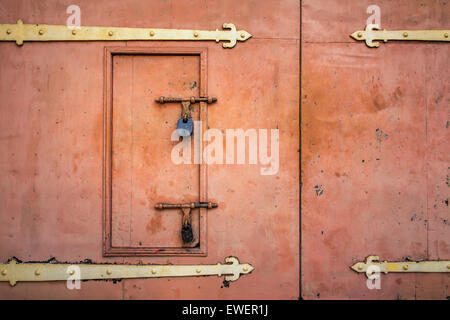 Old rusted padlock hanging on orange metal retro door Stock Photo