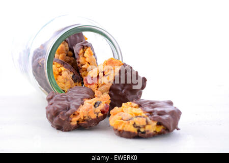 French style Florentine biscuits falling out of glass cookie jar on white shabby chic table. Stock Photo