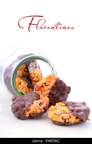 French style Florentine biscuits falling out of glass cookie jar on white shabby chic table. Stock Photo