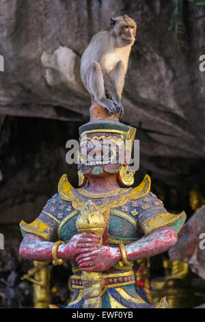 Monkey seats on the buddist statue. Thailand. Stock Photo