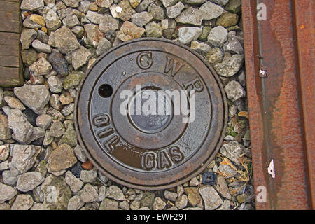 A cast Iron cover for a fuel tap set in the Ballast next to the tracks at a station with the words-GWR OIL GAS. Stock Photo
