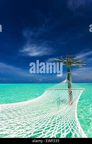 Empty over-water hammock in the middle of tropical lagoon in Maldives Stock Photo