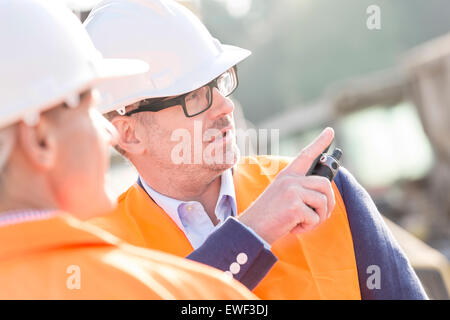 Supervisor showing something to colleague at construction site Stock Photo