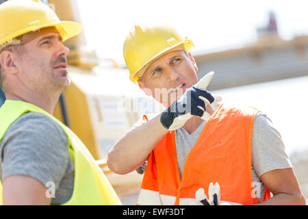 Supervisor showing something to colleague at construction site on sunny day Stock Photo