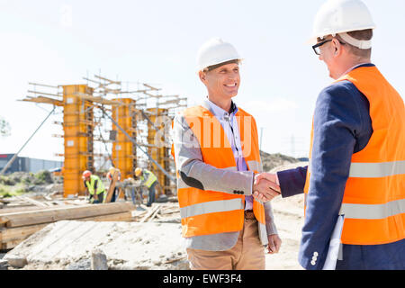 Engineers shaking hands at construction site against clear sky Stock Photo