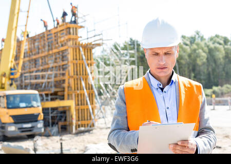 Supervisor writing on clipboard at construction site Stock Photo