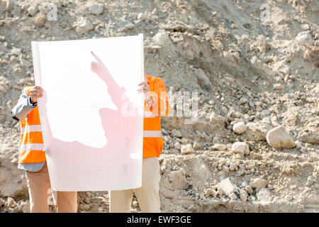 Engineers examining blueprint at construction site Stock Photo