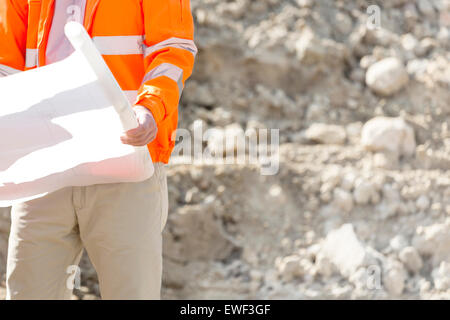 Midsection of supervisor holding blueprint at construction site Stock Photo