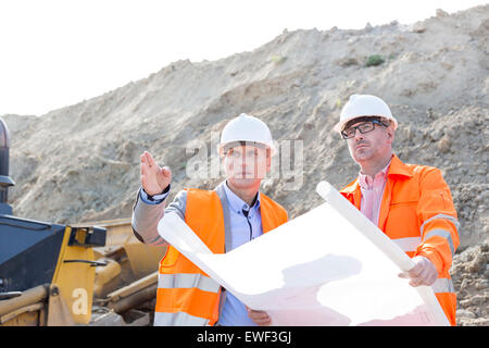 Engineers discussing over blueprint at construction site Stock Photo