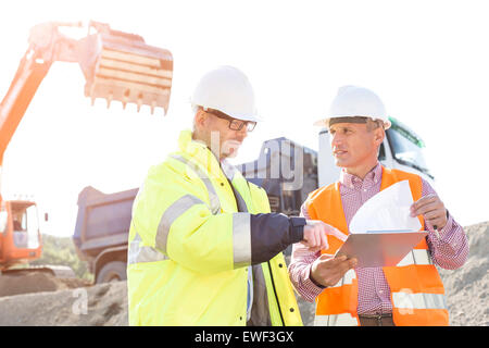 Engineers discussing over documents at construction site Stock Photo
