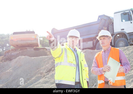 Supervisor showing something to colleague while discussing at construction site Stock Photo