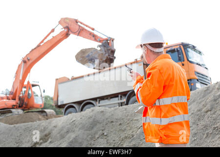 Side view of architect using walkie-talkie while working at construction site Stock Photo