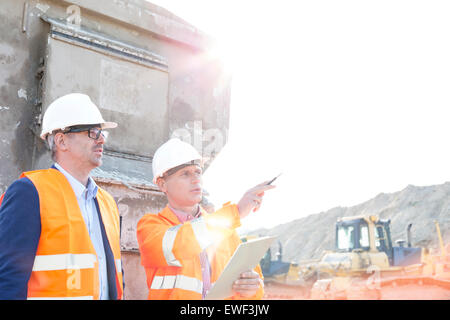 Supervisor showing something to colleague at construction site on sunny day Stock Photo