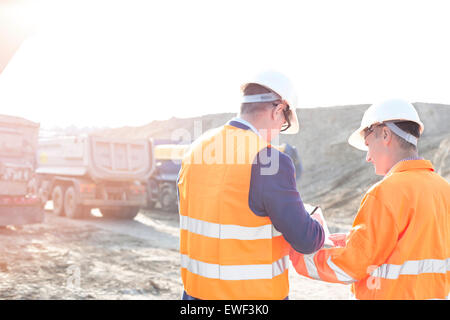 Engineers writing on clipboard at construction site against clear sky Stock Photo