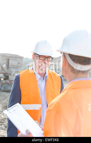 Happy engineers discussing at construction site against clear sky Stock Photo