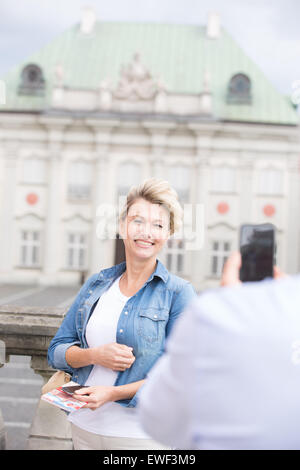 Cropped image of man photographing woman outside building Stock Photo