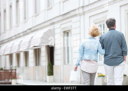 Rear view of middle-aged couple walking by building Stock Photo