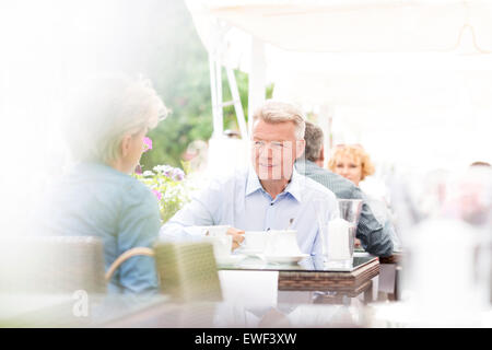 Middle-aged couple sitting at sidewalk cafe on sunny day Stock Photo