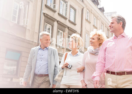 Happy friends talking while walking in city Stock Photo