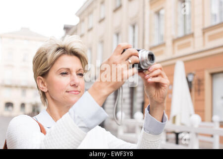 Woman photographing through digital camera in city Stock Photo