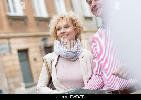 Happy middle-aged couple with map in city Stock Photo