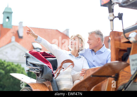 Middle-aged woman showing something to man while sitting in horse cart Stock Photo