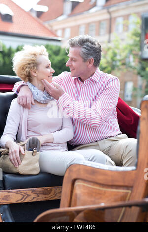 Romantic middle-aged couple sitting in horse cart Stock Photo