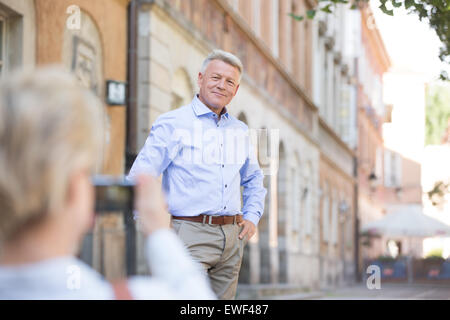Middle-aged woman taking picture of man in city Stock Photo