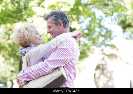 Side view of middle-aged couple embracing while looking at each other in park Stock Photo