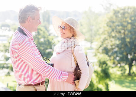 Side view of middle-aged couple embracing while looking at each other in park Stock Photo