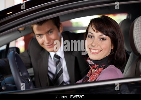 Portrait of young couple sitting in a new car at showroom Stock Photo