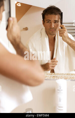 Young man combing his hair Stock Photo