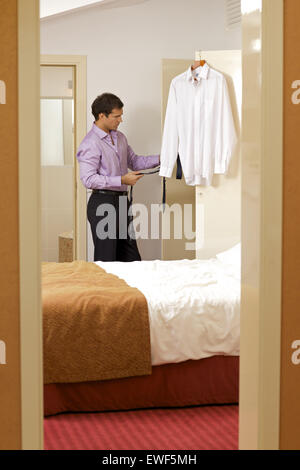 Young man holding tie in hotel room Stock Photo