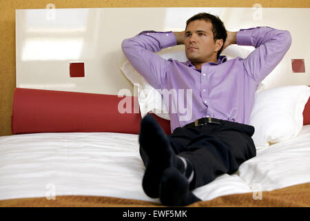 Man relaxing in hotel room with hands behind head Stock Photo