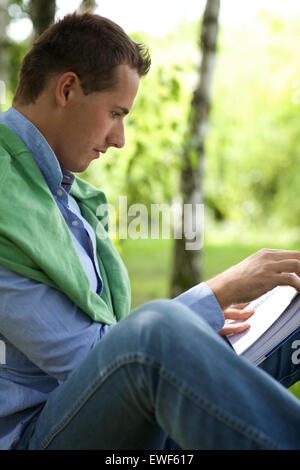 Young man reading book in park Stock Photo