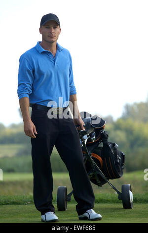 Portrait of young man carrying trolley with golf bag Stock Photo