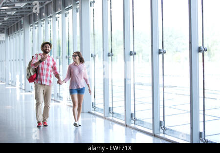 Full-length of couple holding hands while walking at covered passage Stock Photo