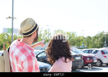 Man showing something to woman on city street against clear sky Stock Photo