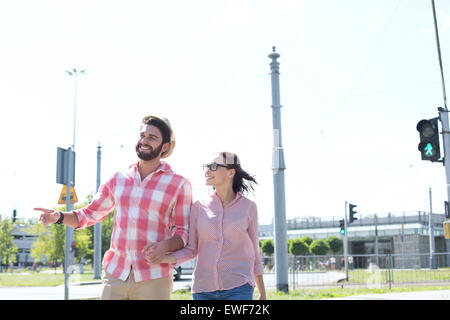 Happy couple walking in city against clear sky Stock Photo