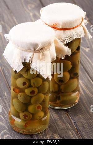 Pickled olives in jar on wooden table Stock Photo