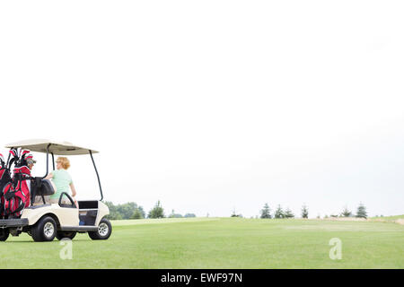 Couple sitting in golf cart against clear sky Stock Photo