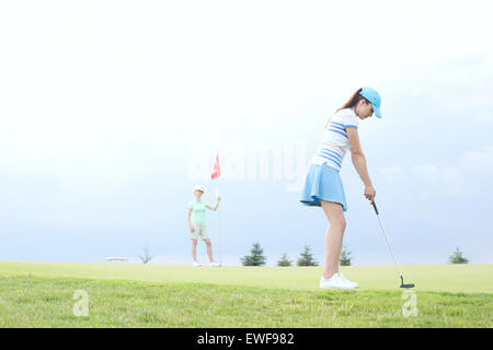 Woman playing golf with female friend against sky Stock Photo