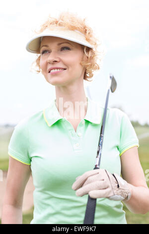 Thoughtful middle-aged woman looking away while holding golf club Stock Photo