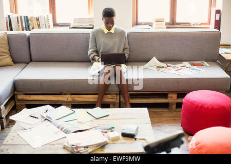 Creative businesswoman typing on digital tablet on sofa in office Stock Photo