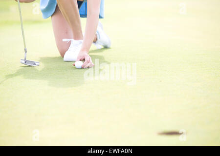 Low section of woman placing ball at golf course Stock Photo