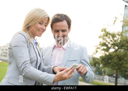 Happy business couple using smart phone at park Stock Photo