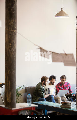 Casual businessmen working at laptop on sofa in office Stock Photo